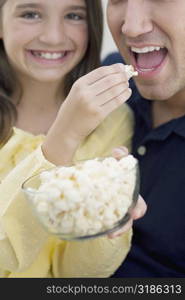 Portrait of a girl feeding popcorn to her father