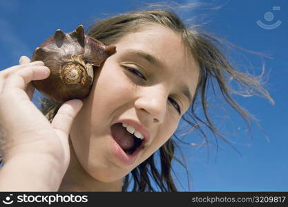 Portrait of a girl holding a conch shell to her ear