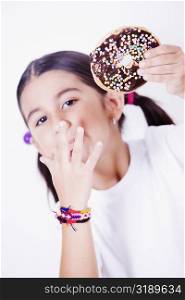Portrait of a girl holding a donut and licking her finger