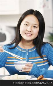 Portrait of a girl holding a pair of chopsticks and a bowl