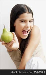 Portrait of a girl holding a pear and screaming