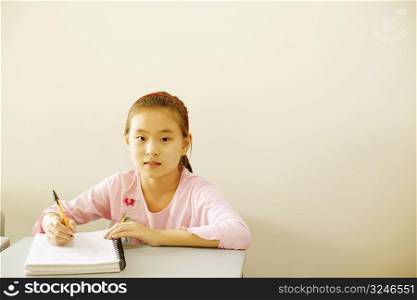 Portrait of a girl holding a pen on a spiral notebook in the classroom