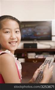 Portrait of a girl holding a remote control and smiling