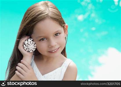 Portrait of a girl holding a shell near her ear and smiling