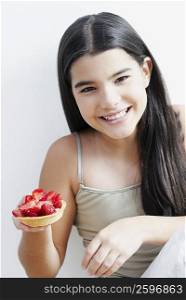 Portrait of a girl holding a strawberry tart and smiling