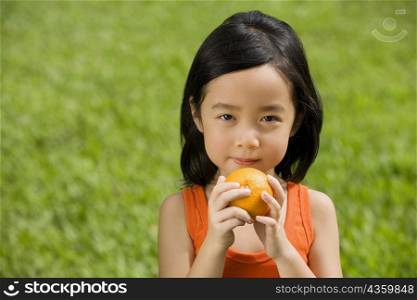 Portrait of a girl holding an orange