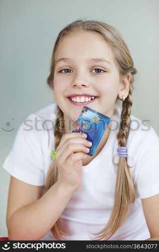 Portrait of a girl holding credit card over gray background