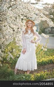 Portrait of a girl in a cherry blossom bush.. A beautiful girl in a hat among the flowering trees 2722.