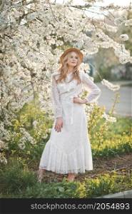 Portrait of a girl in a cherry blossom bush.. A beautiful girl in a hat among the flowering trees 2723.