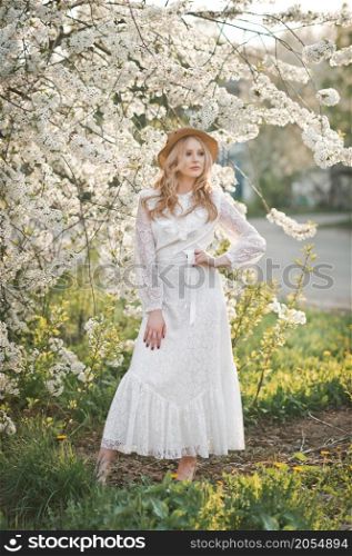Portrait of a girl in a cherry blossom bush.. A beautiful girl in a hat among the flowering trees 2724.
