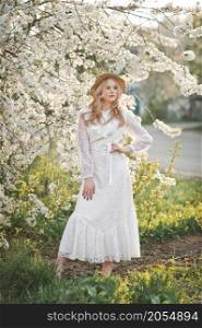 Portrait of a girl in a cherry blossom bush.. A beautiful girl in a hat among the flowering trees 2724.