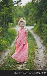 Portrait of a girl in a long dress among the shrubs of the garden.. Childrens portrait of a girl in a beautiful outfit 6647.