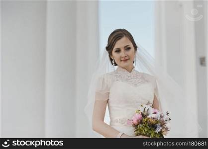 Portrait of a girl in a white dress and veil around the columns.. Portrait of a young bride about the white columns 4022.