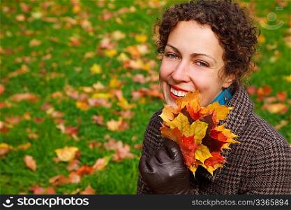 portrait of a girl in autumnal park with bunch of leaves