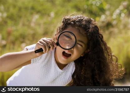Portrait of a girl looking through a magnifying glass