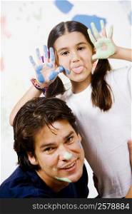 Portrait of a girl making a face with her father smiling beside her