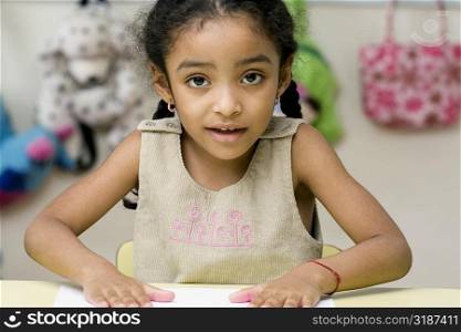 Portrait of a girl making handprints on a sheet of paper