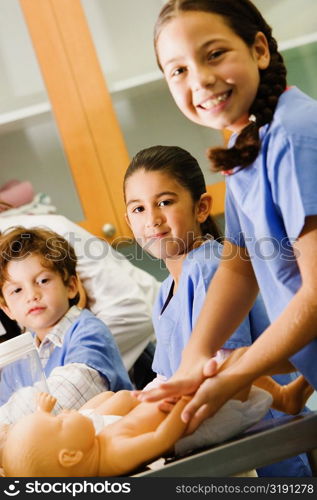 Portrait of a girl massaging a doll with her friends standing beside her