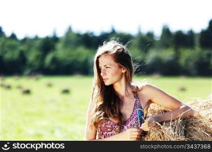 portrait of a girl next to a stack of hay under the blue sky