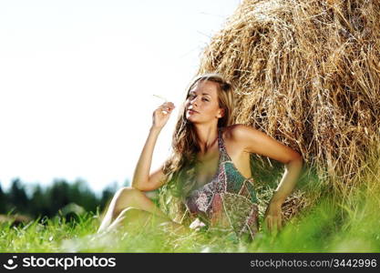 portrait of a girl next to a stack of hay under the blue sky