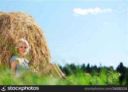 portrait of a girl next to a stack of hay under the blue sky