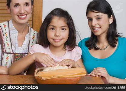 Portrait of a girl preparing bread with her mother and sister in the kitchen