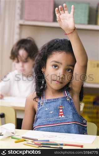 Portrait of a girl raising her hand in a classroom