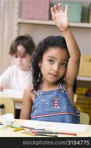 Portrait of a girl raising her hand in a classroom