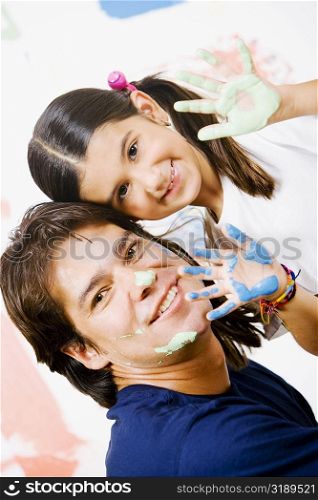 Portrait of a girl showing paint on her palms with her father smiling