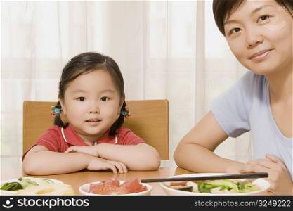 Portrait of a girl sitting at a dining table with her mother