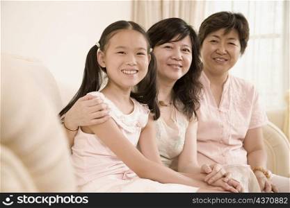 Portrait of a girl sitting on a couch with her mother and grandmother