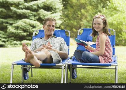 Portrait of a girl sitting on a lounge chair beside her father
