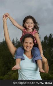 Portrait of a girl sitting on her mother&acute;s shoulders and smiling