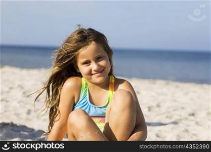 Portrait of a girl sitting on the beach and smiling