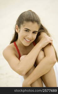 Portrait of a girl sitting on the beach smiling