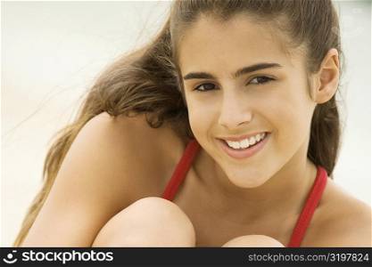 Portrait of a girl sitting on the beach smiling