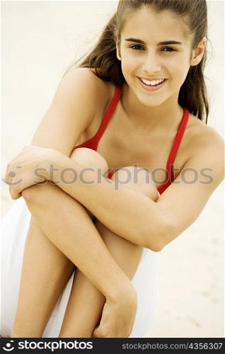 Portrait of a girl sitting on the beach smiling