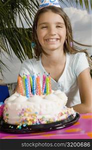 Portrait of a girl smiling in front of a birthday cake