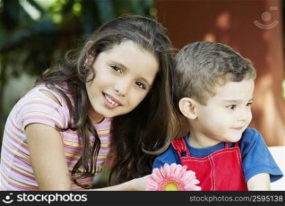 Portrait of a girl smiling with a boy beside her