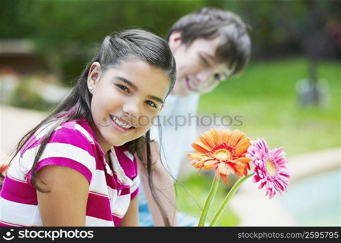 Portrait of a girl smiling with a boy sitting beside her