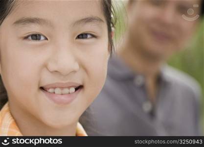 Portrait of a girl smiling with her father in the background