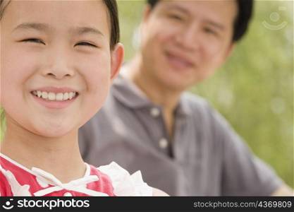 Portrait of a girl smiling with her father in the background