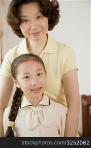 Portrait of a girl smiling with her grandmother behind her