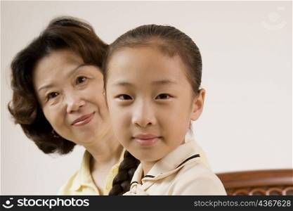 Portrait of a girl smiling with her grandmother behind her