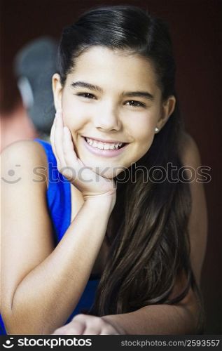 Portrait of a girl smiling with her hand on her chin
