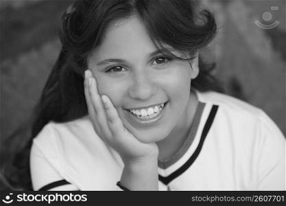 Portrait of a girl smiling with her hand on her chin