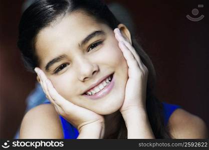 Portrait of a girl smiling with her hands on her chin