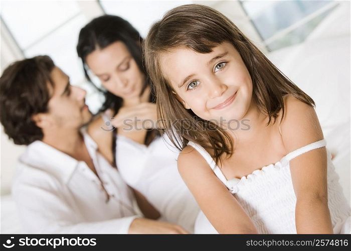 Portrait of a girl smiling with her parents behind her
