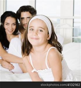 Portrait of a girl smiling with her parents behind her