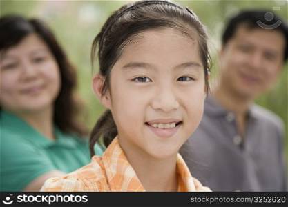 Portrait of a girl smiling with her parents in the background